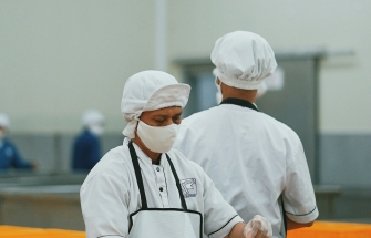 Chef-kok in wit uniform snijdt vlees in professionele voedingsverwerking
