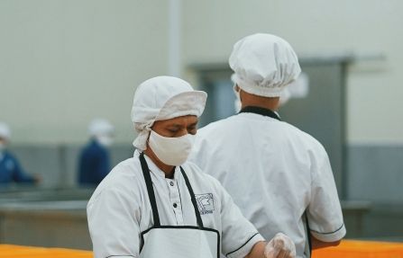 Chef-kok in wit uniform snijdt vlees in professionele voedingsverwerking
