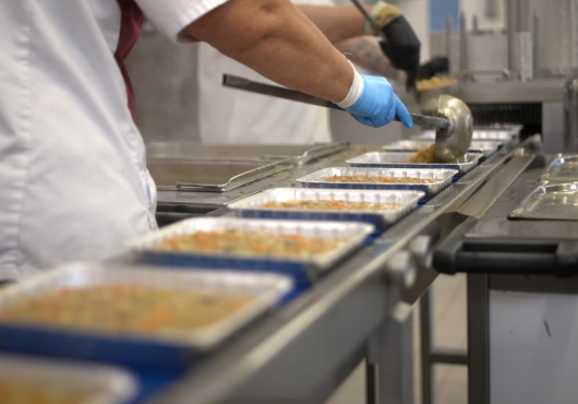 Medewerker vult voedselbakjes op een productielijn